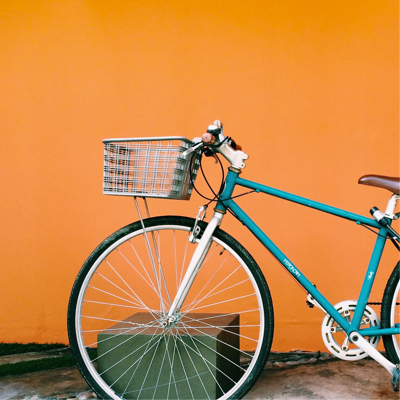 a blue bike with a basket in front of an orange wall
